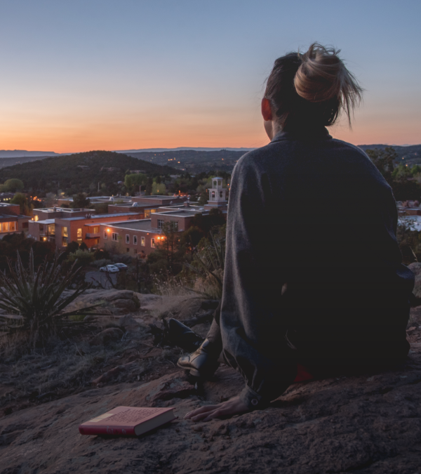 A student sitting above the santa fe campus at sunset